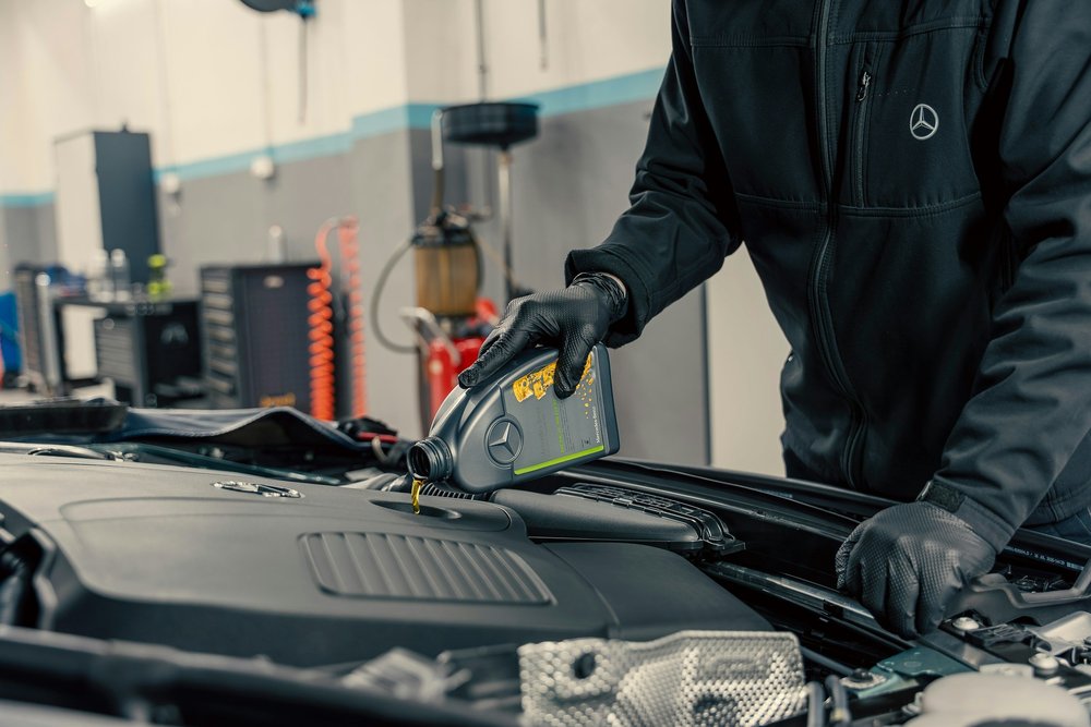 Technician pouring motor oil into a car engine